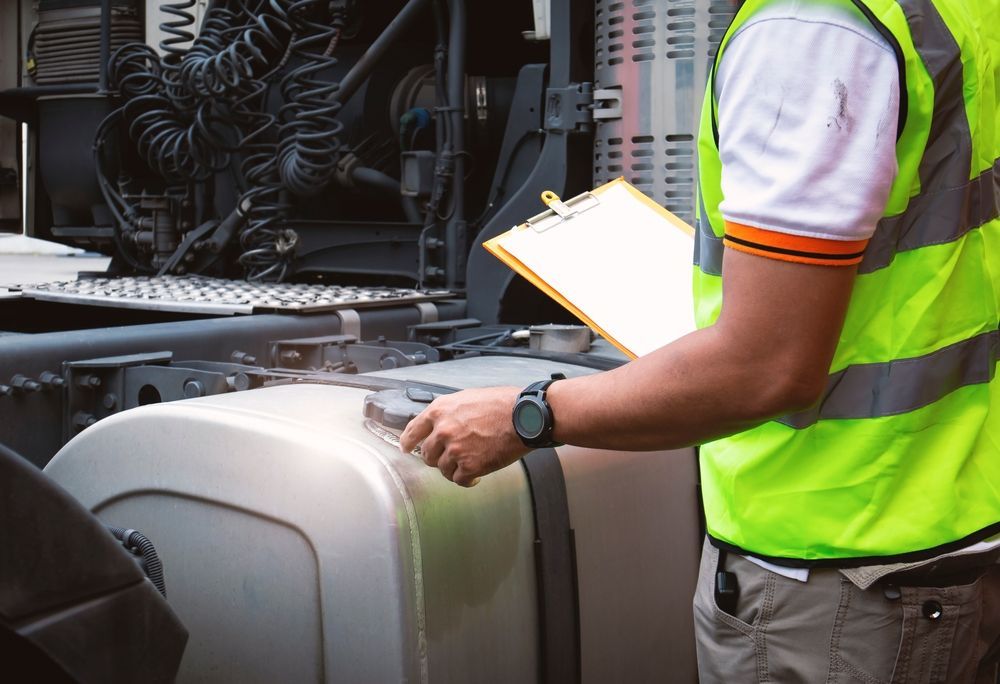 A Man in A Yellow Vest Is Standing Next to A Semi Truck Holding a Clipboard — Top End Diesel In Katherine, NT
