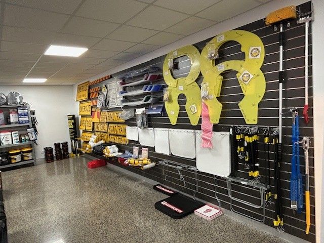 A retail display of auto parts, with signs, wipers, and safety items arranged on black slat walls — Top End Diesel In Wishart, NT