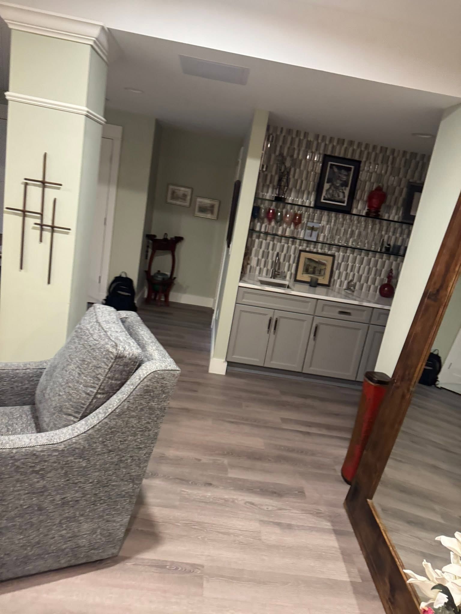 Living room with gray sofa, wood floor, and built-in cabinet wall with patterned wallpaper