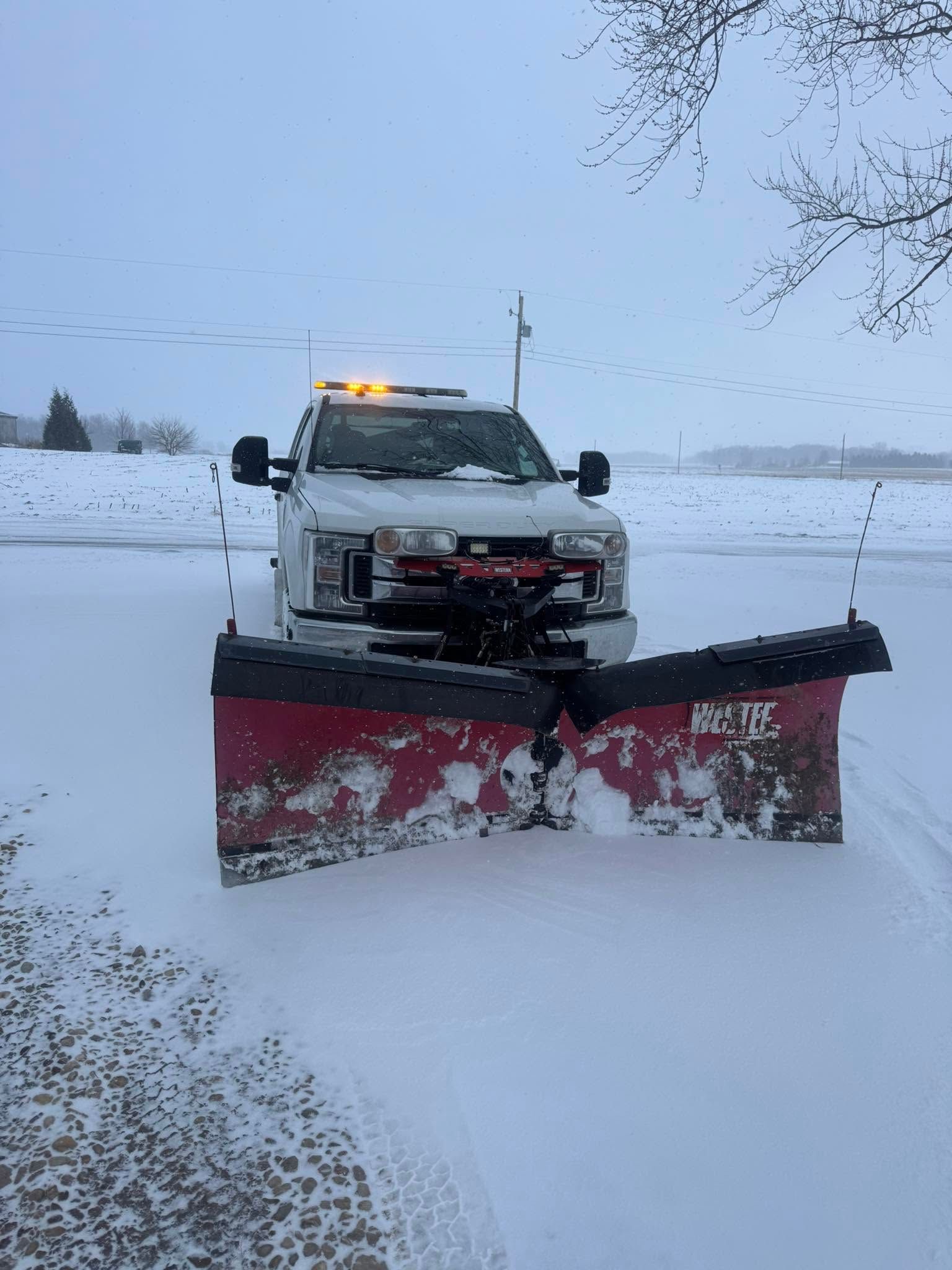 Snowplow truck clearing a snowy road during a winter storm