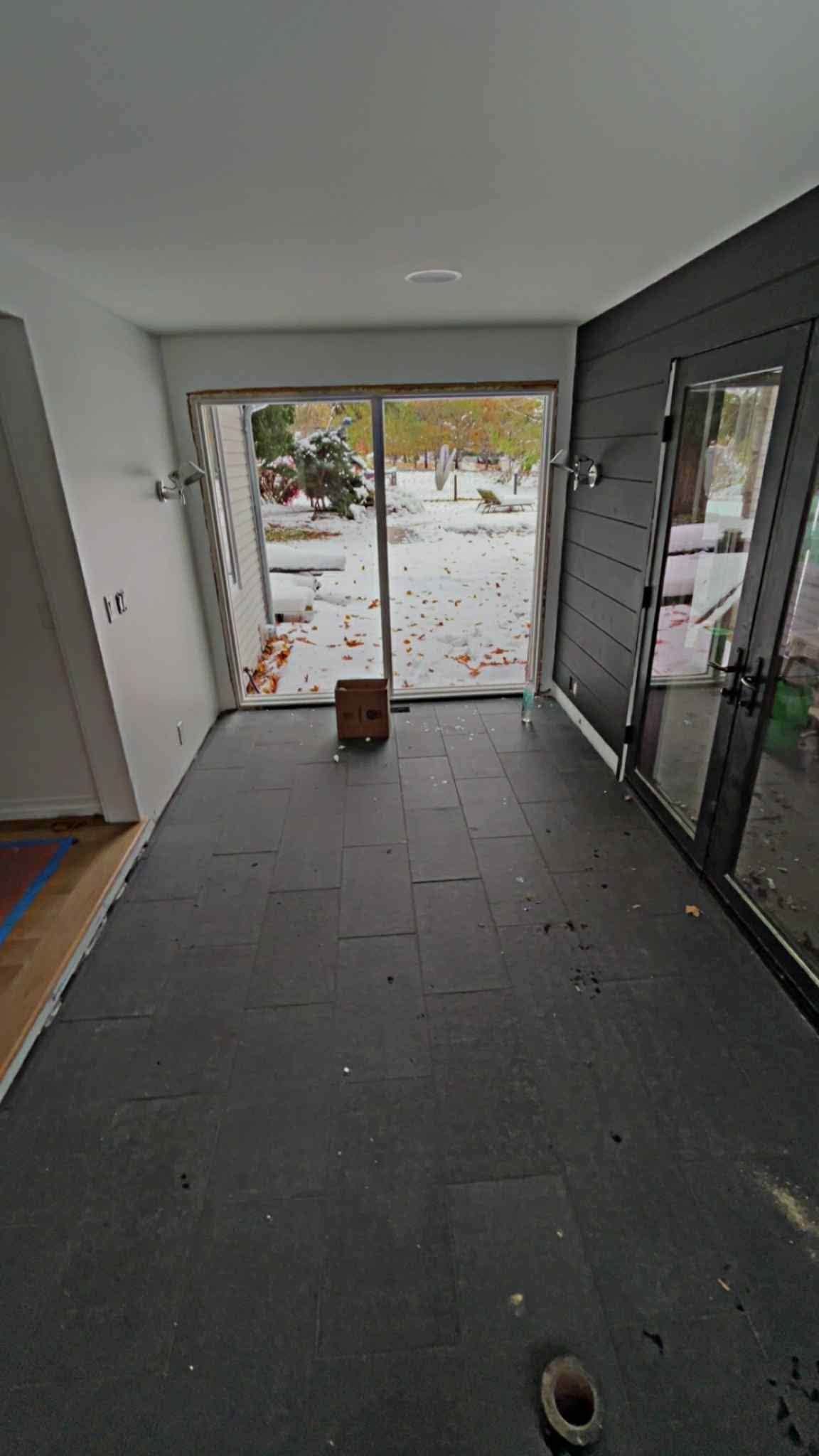 Modern entryway with dark floor, glass doors, and a view of snowy outdoors
