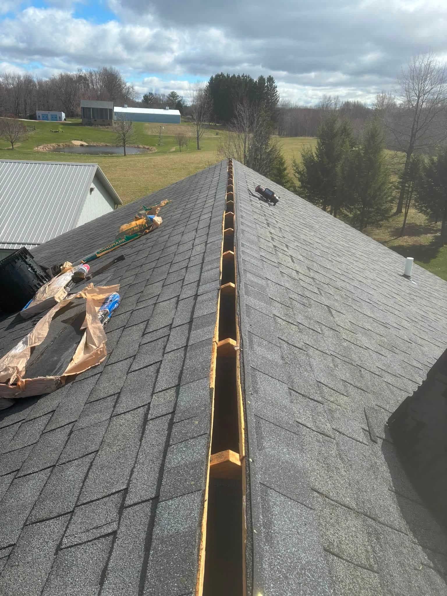 Roof viewed from the peak, with shingles removed along the ridge exposing the roof deck and an open valley.