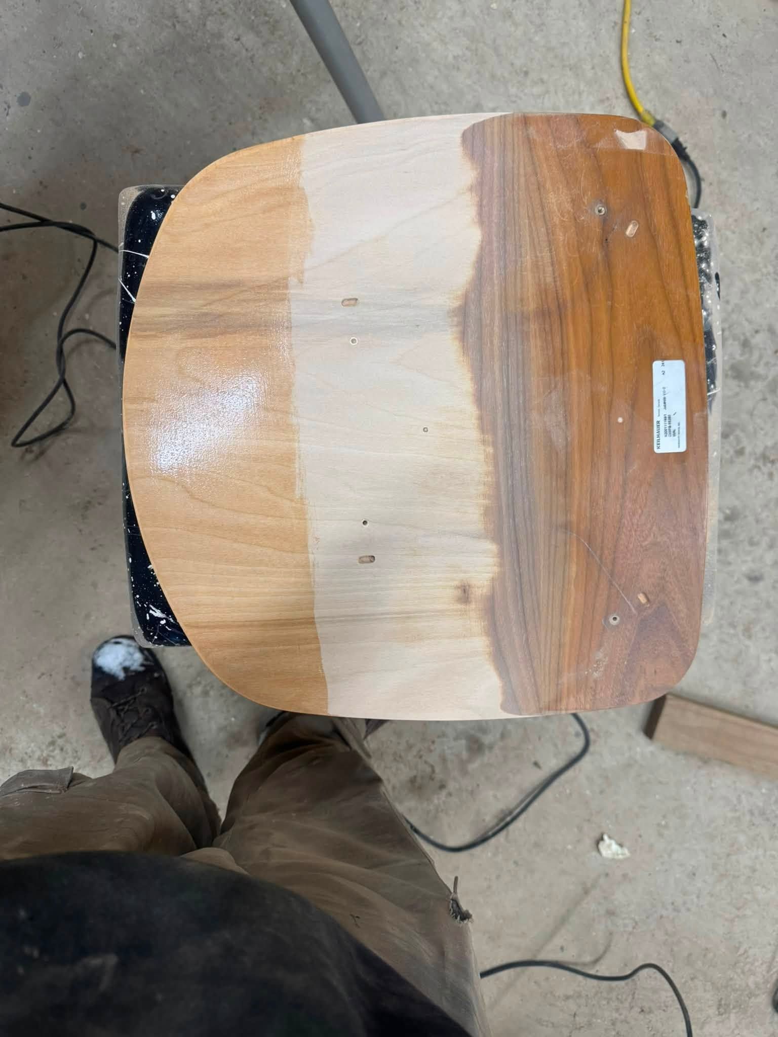 Wooden tabletop with a white painted center stripe on a concrete floor, with a shoe and cords nearby