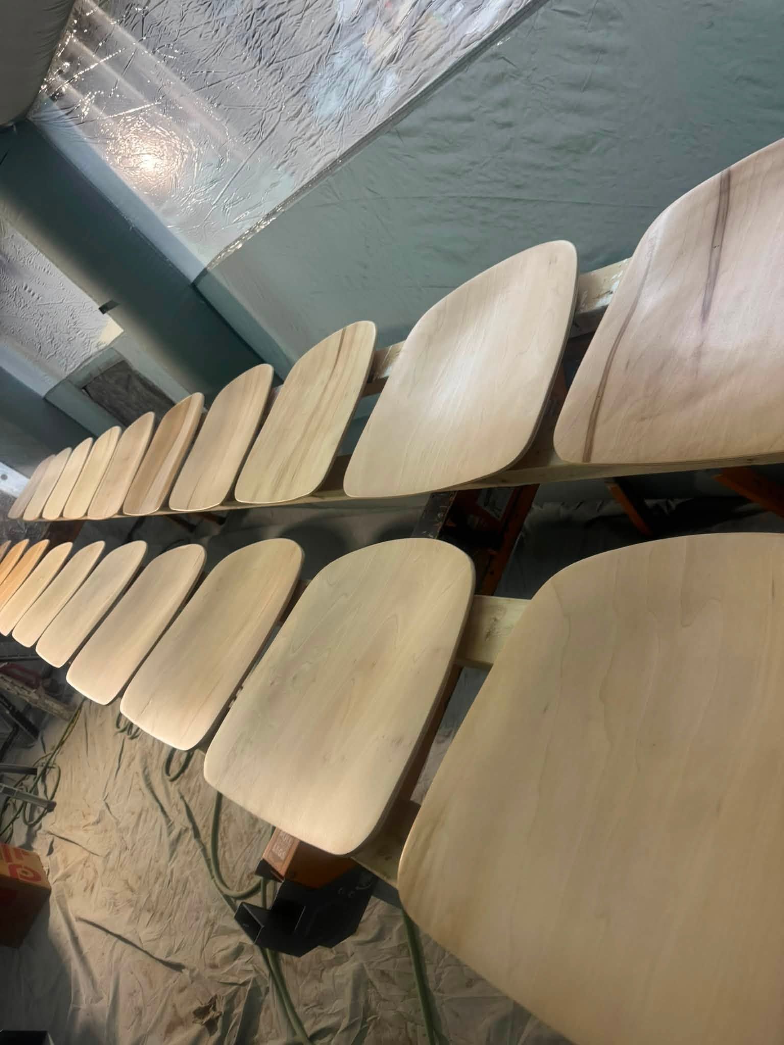 Rows of pale wooden paddle-shaped pieces displayed on shelves under a tarp canopy
