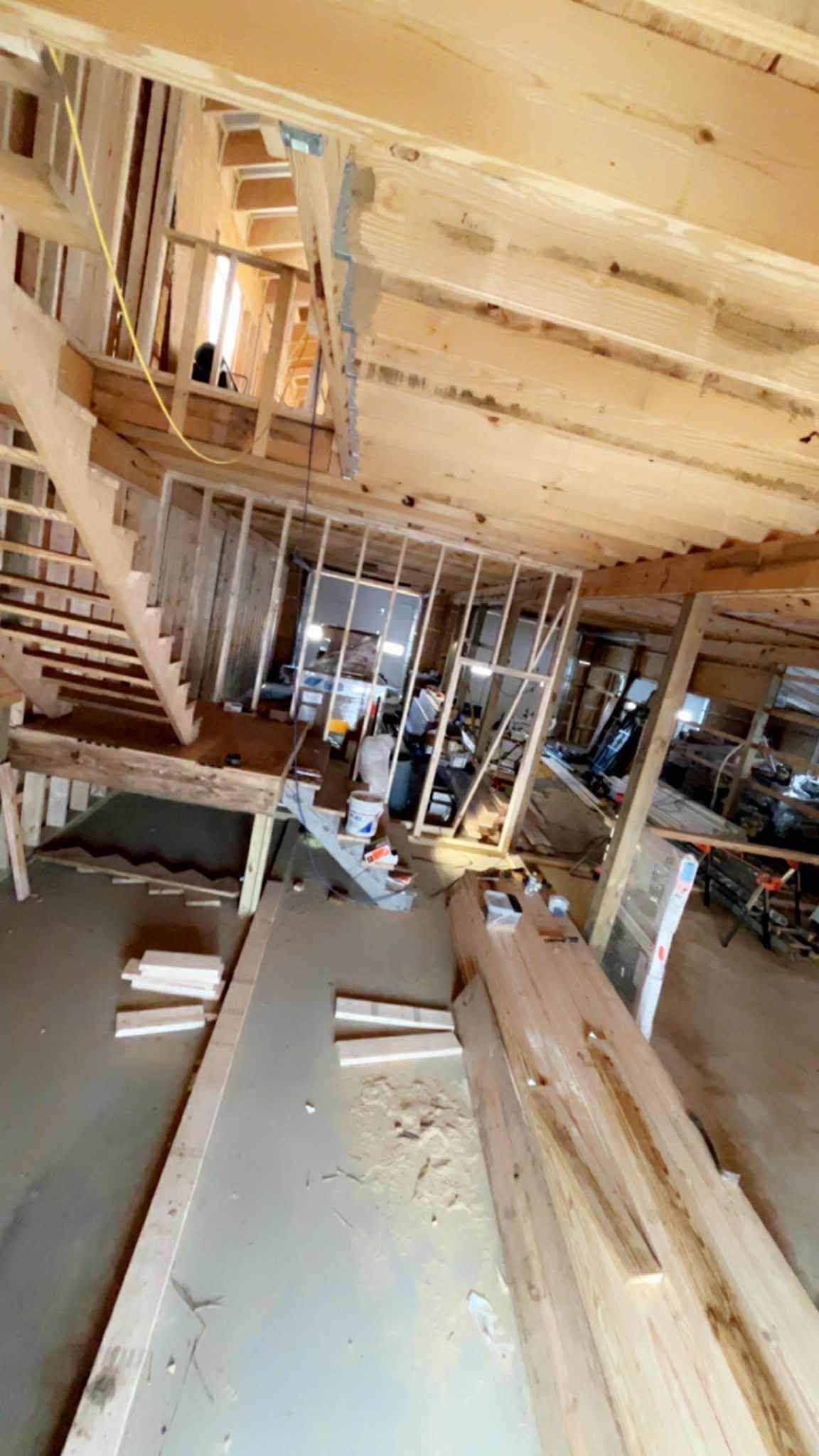 Interior of a house under construction with exposed wooden framing and scattered building materials.