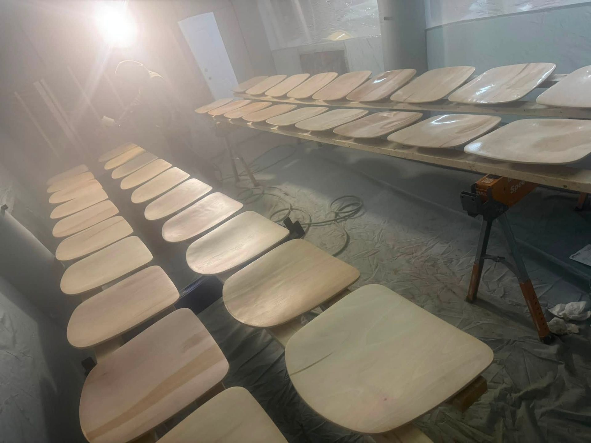 Rows of wooden chairs arranged in a bright room with sunlight streaming in from the left.