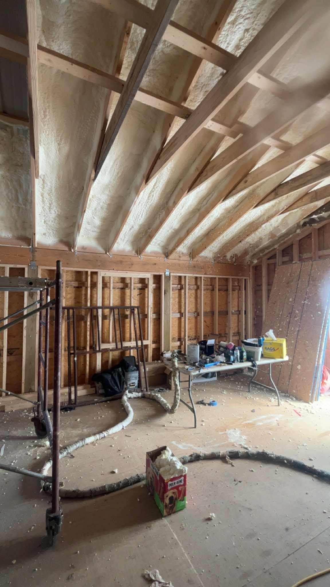 Partially finished room with exposed framing, insulated ceiling, and construction tools on the floor