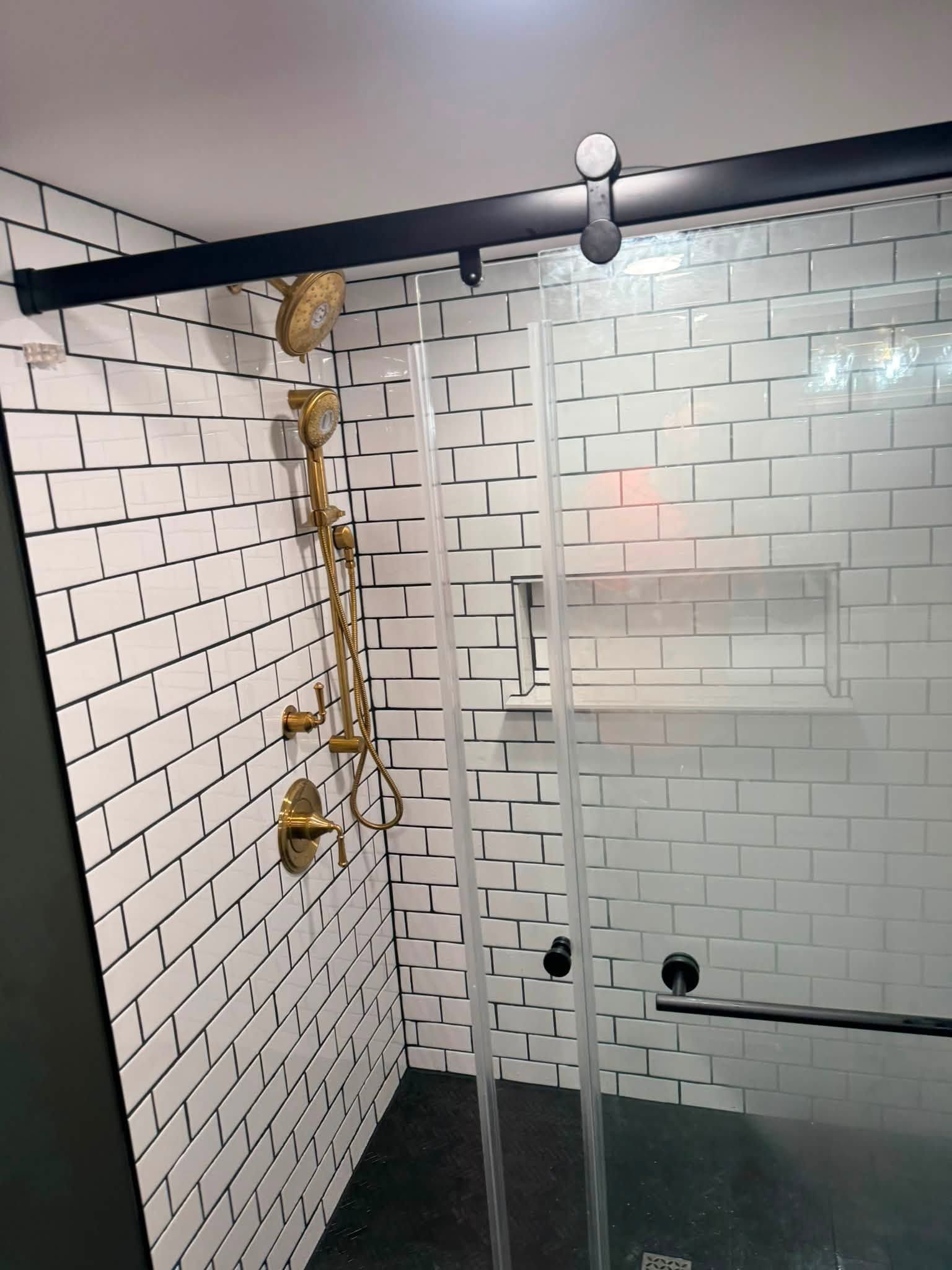 Skeleton decoration hanging in a white-tiled shower with a glass partition and black shower rod