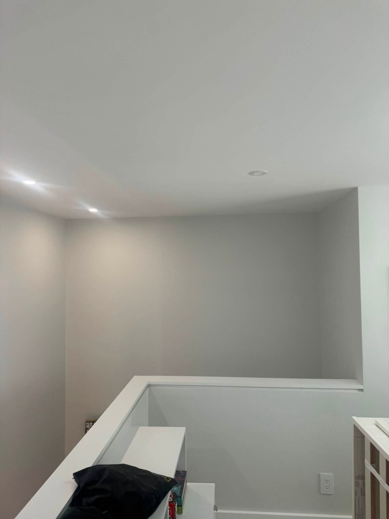 Empty stairwell with gray walls, white railing, and a ceiling light.