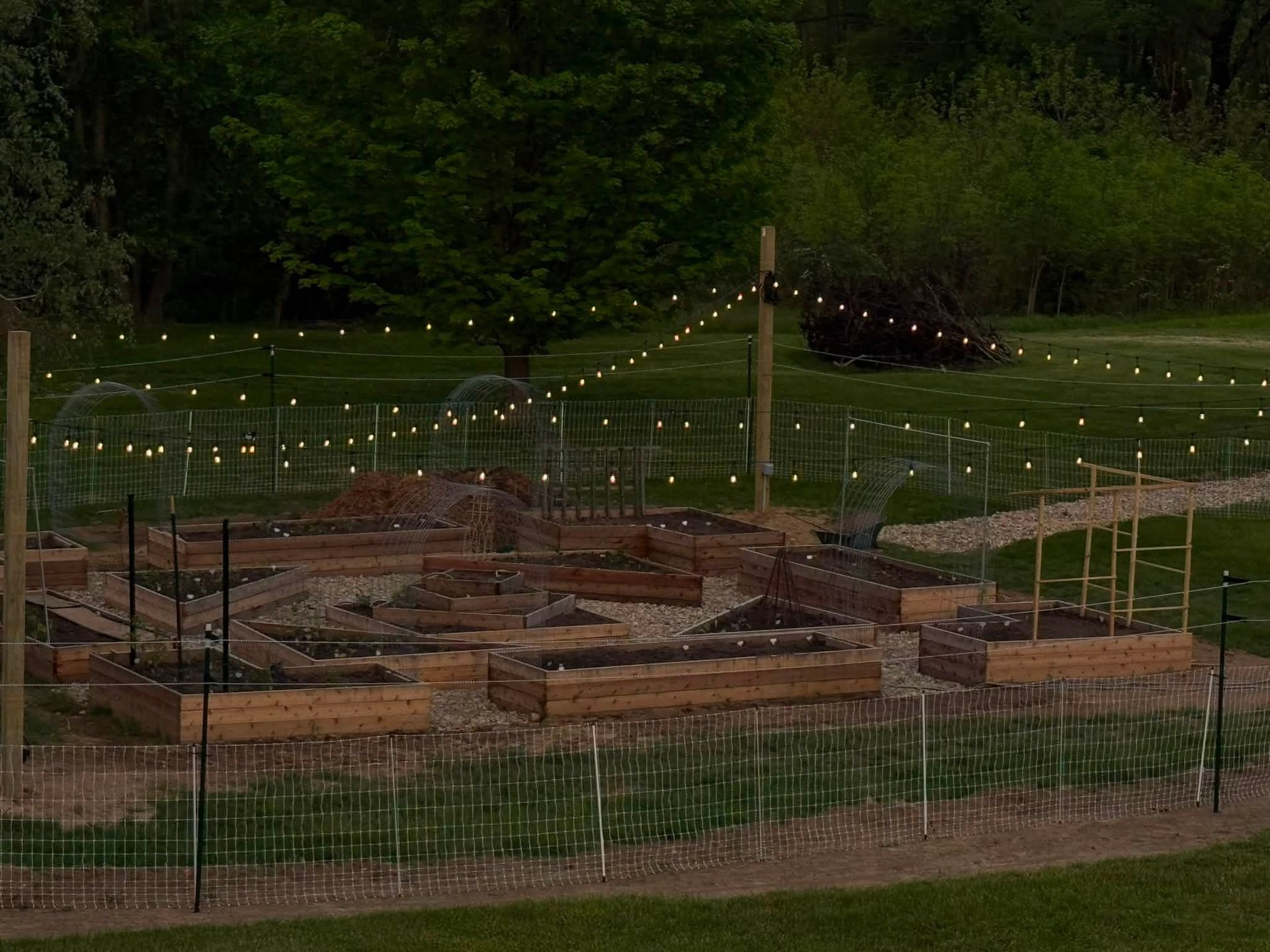 Water-filled garden beds and a fenced layout in a lush green outdoor garden