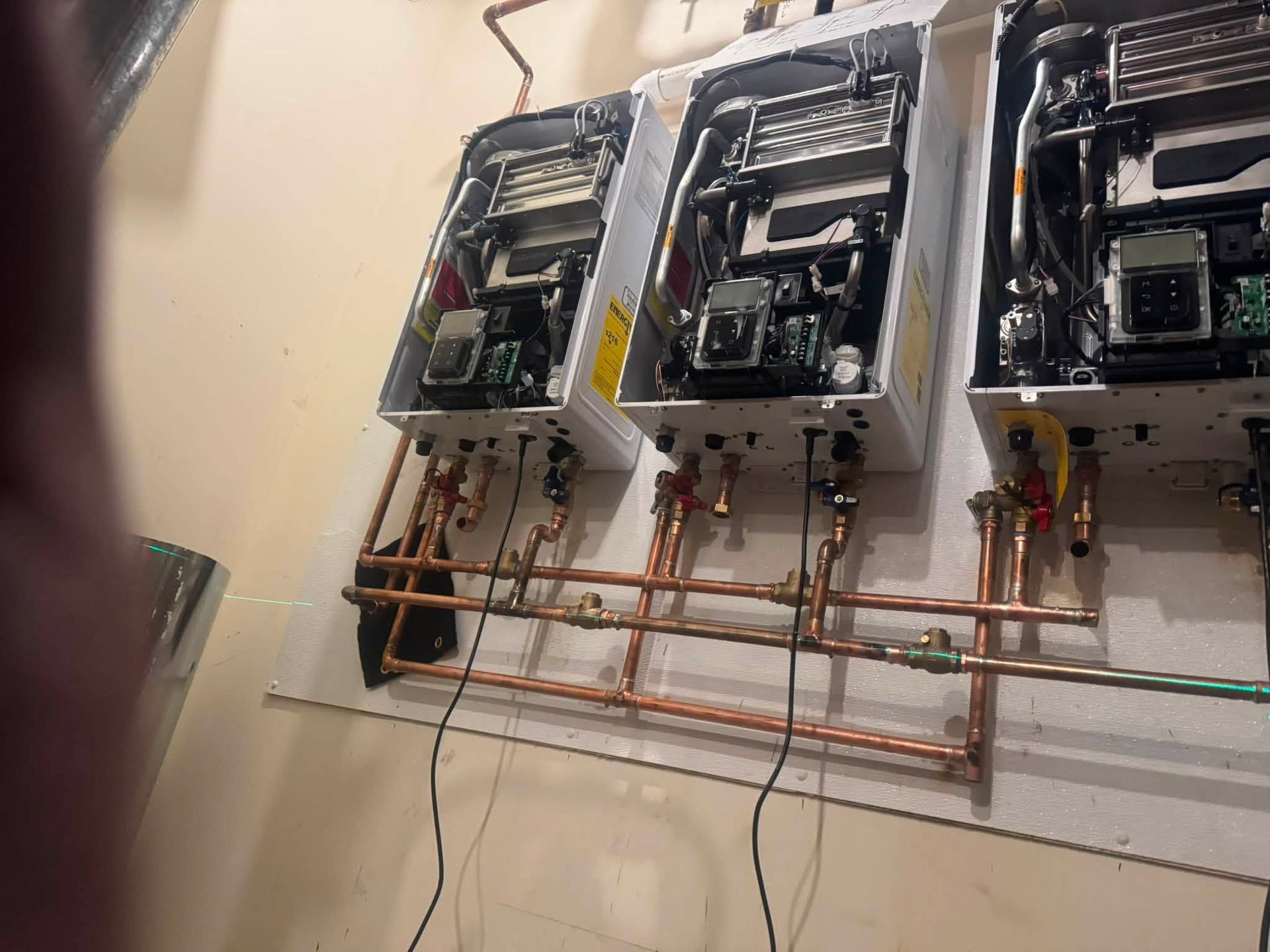 Three wall-mounted utility meters with copper piping in a basement or utility room.