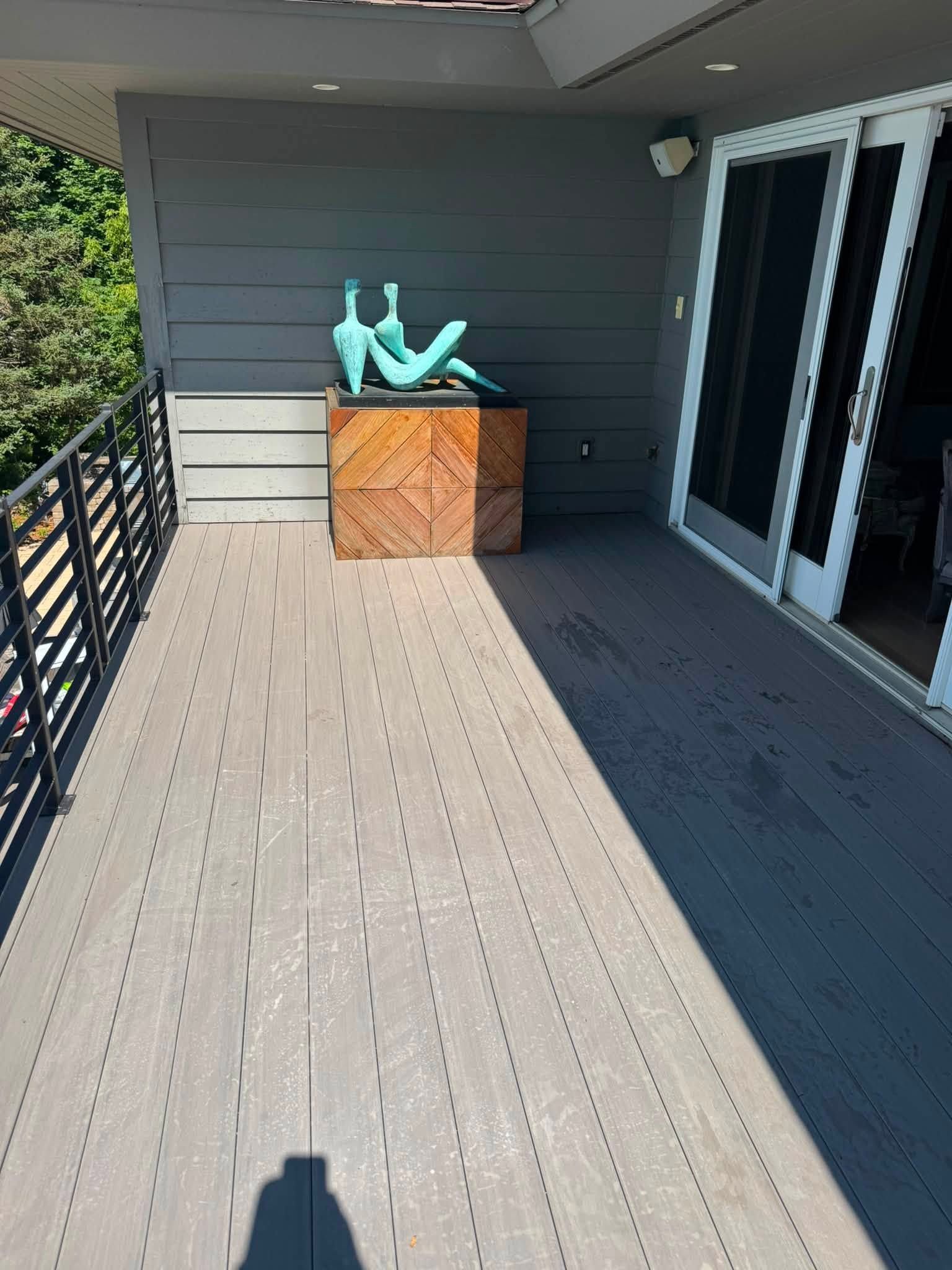 Covered balcony with a wooden storage chest and turquoise objects against a gray wall.