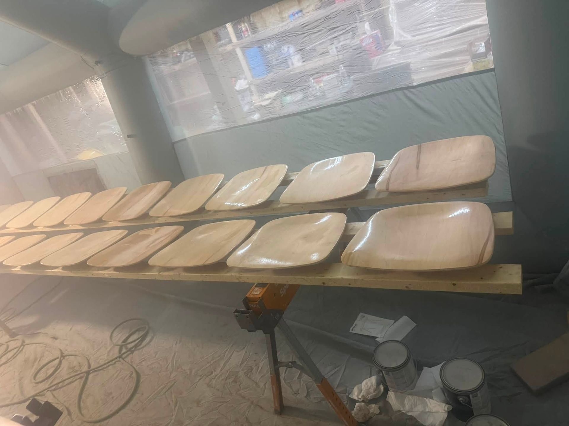 Rows of beige cushions or pads on a long table in a workshop, with tools and supplies nearby.
