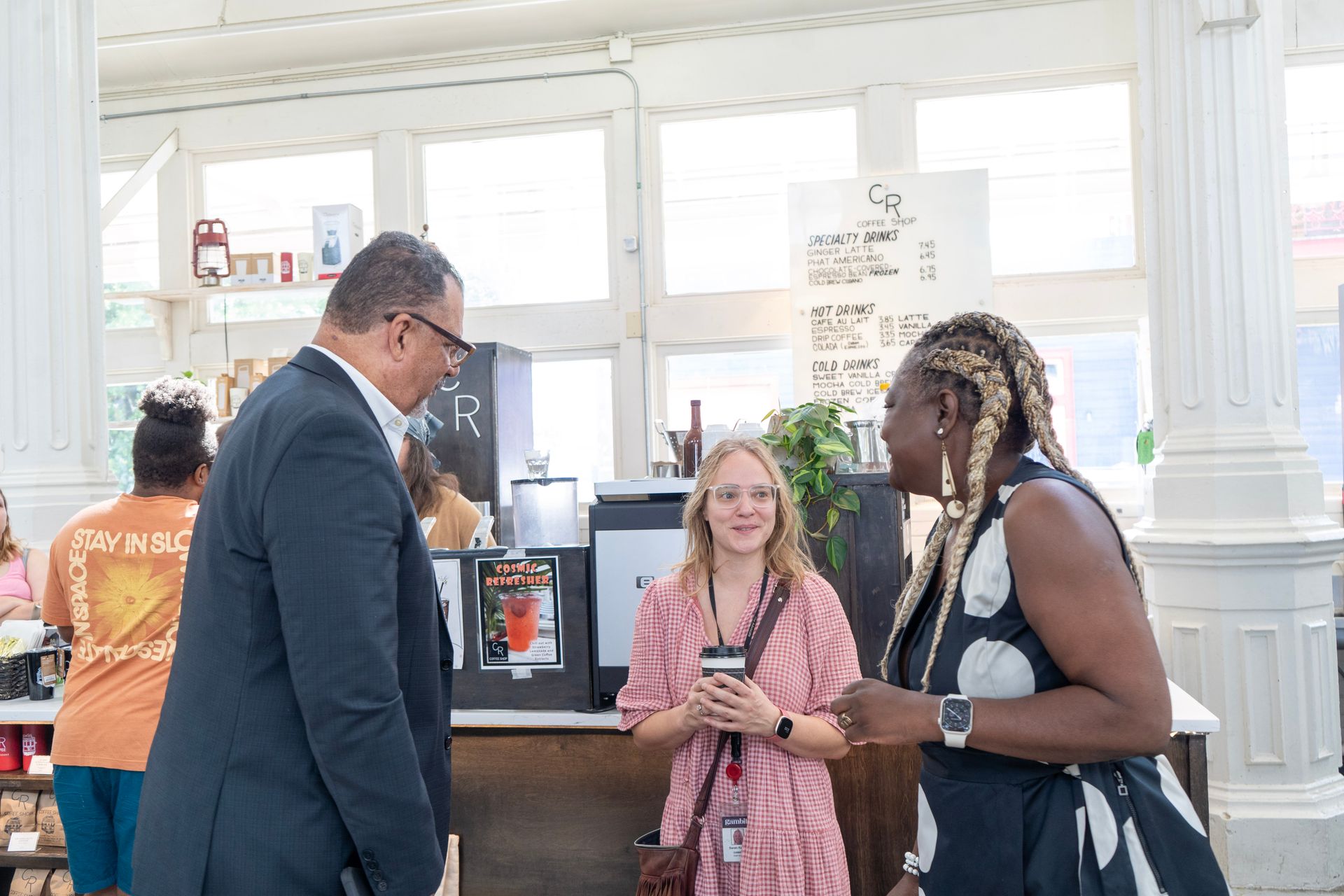 Oliver Thomas in a suit and tie is standing next to a woman in a kitchen.