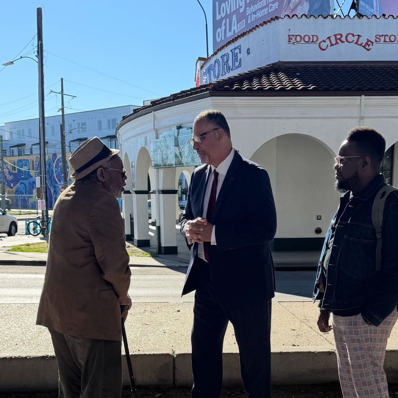Oliver Thomas and two other men are standing in front of a building that says food circle