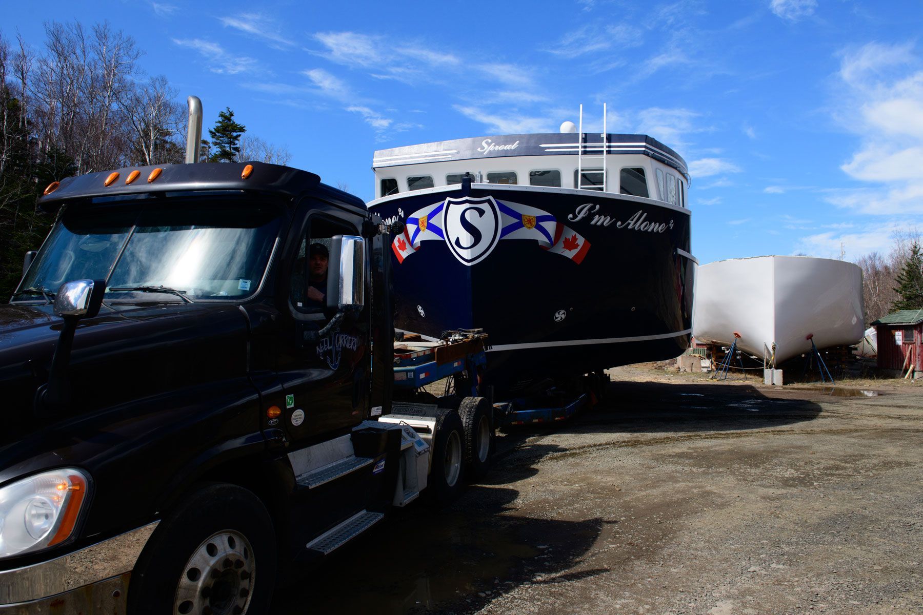 A boat with the letter s on it is being towed by a truck