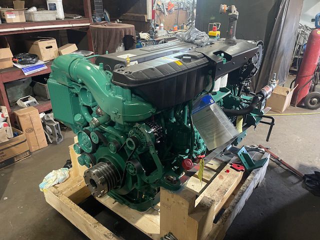 A green engine is sitting on a wooden pallet in a garage.