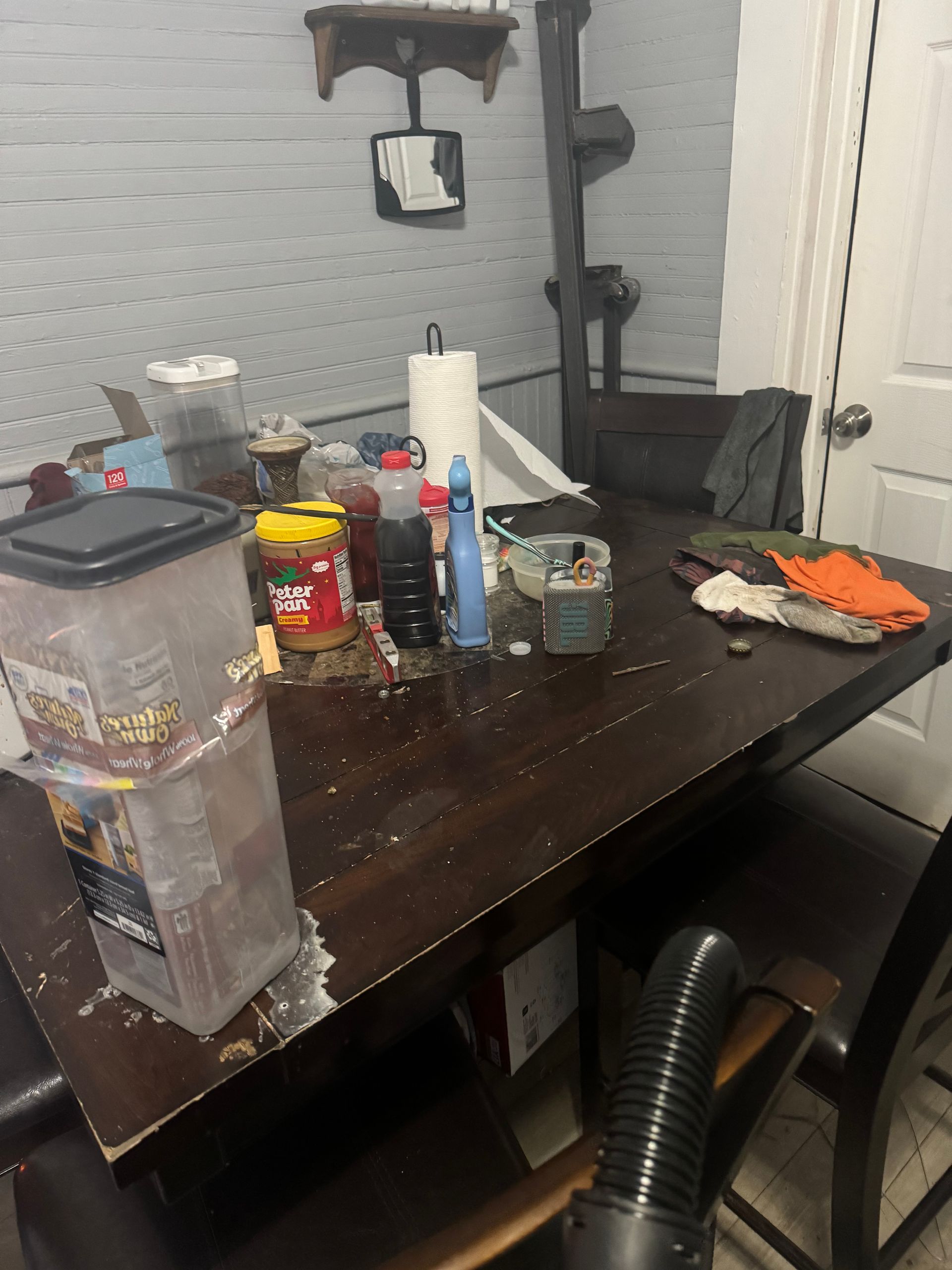 A messy dining room table with a vacuum cleaner on it.