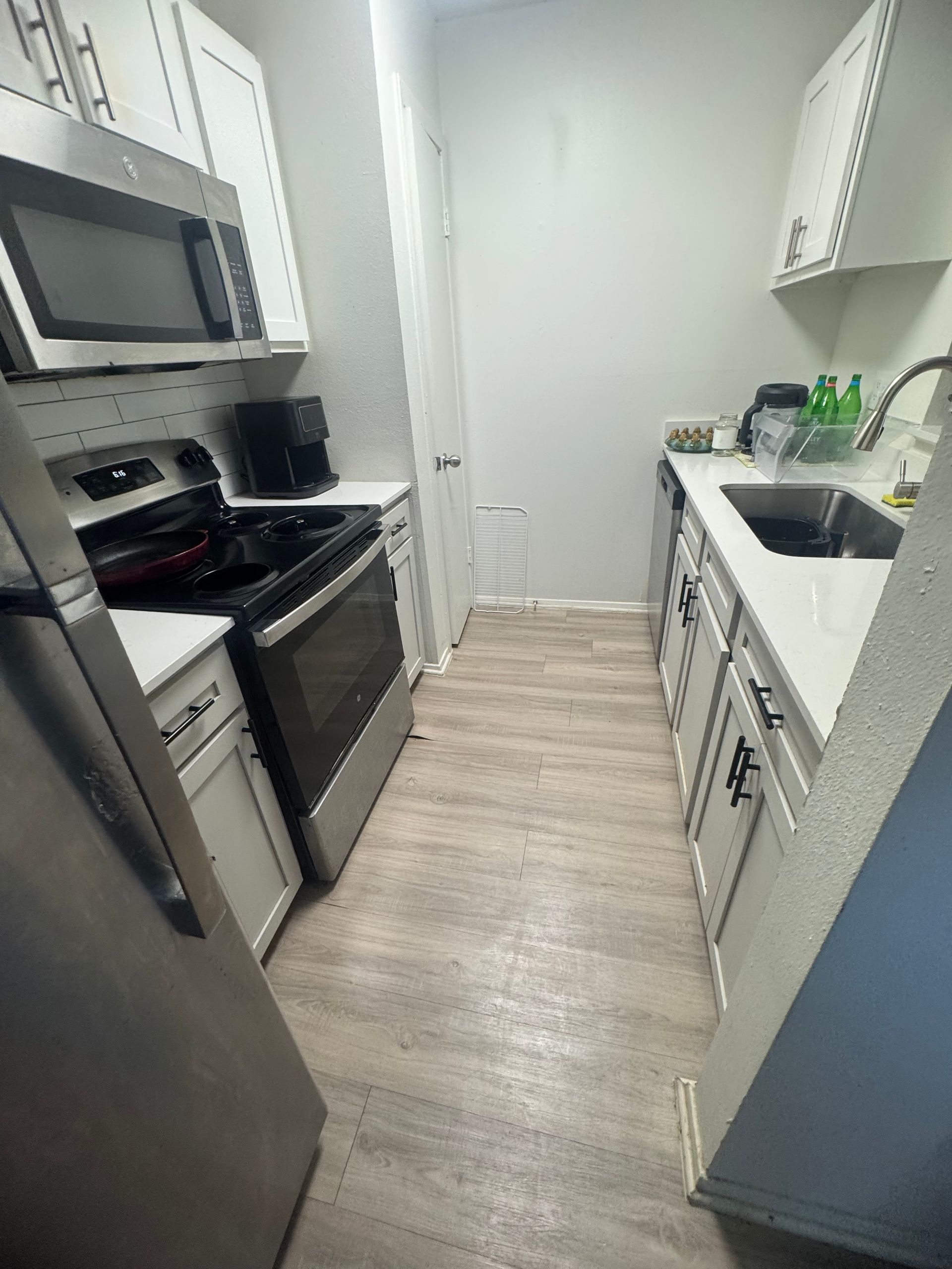 A kitchen with a stove, refrigerator, microwave, and sink.