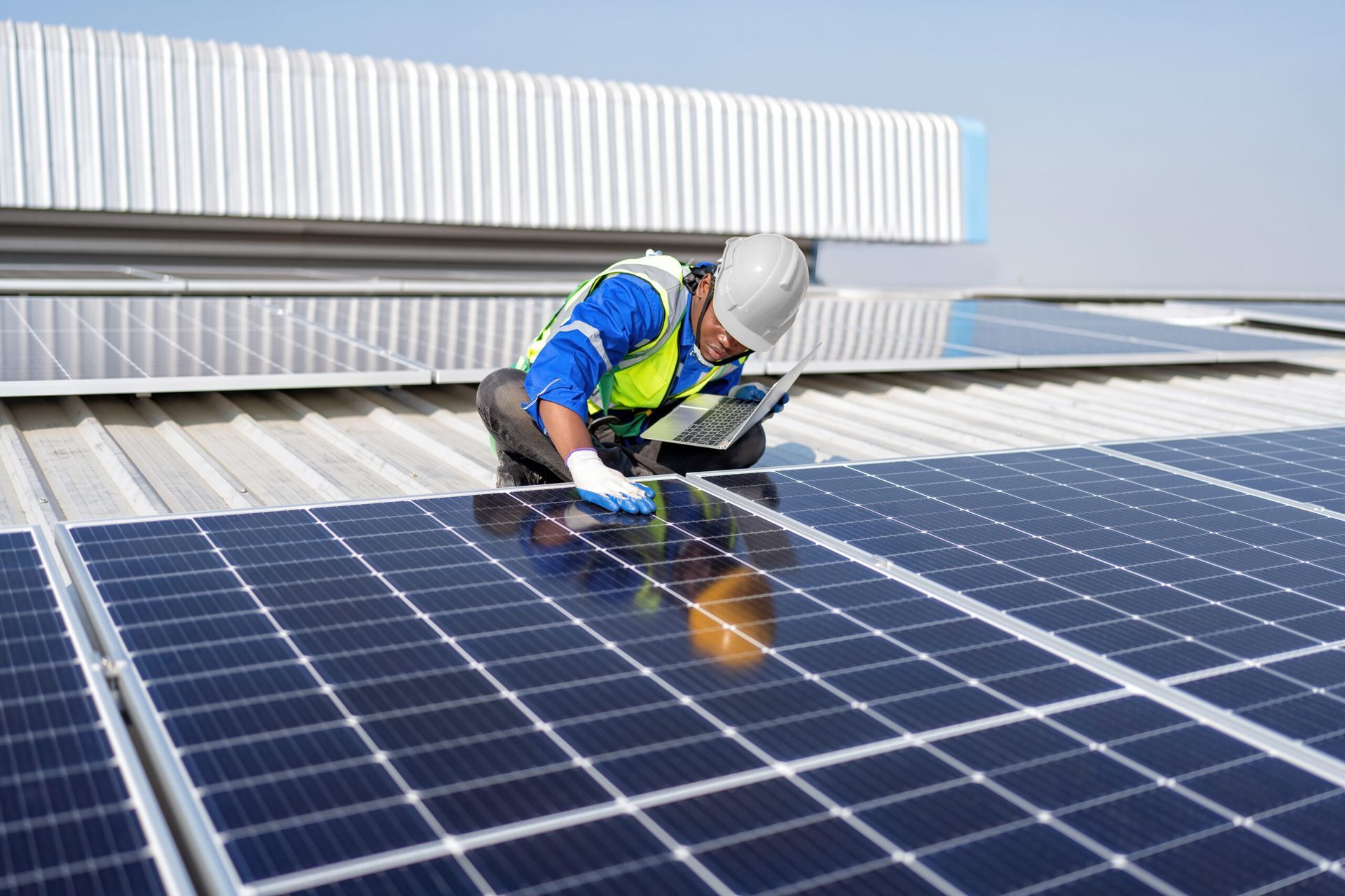 Un homme travaille sur un panneau solaire sur le toit d'un bâtiment.
