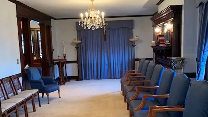 A church chapel with blue curtains, chairs, and a chandelier.
