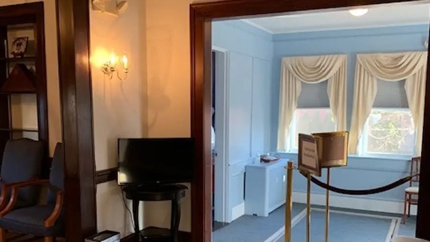 Interior view: Doorway leading to blue room with windows and draped curtains.