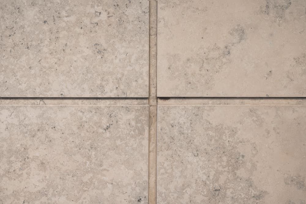 A close up of a tiled floor with a gray grout line between the tiles.