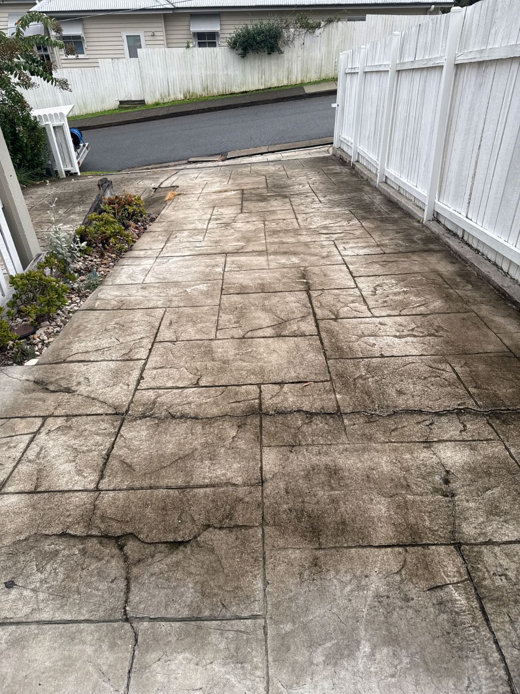 A dirty concrete driveway leading to a house.