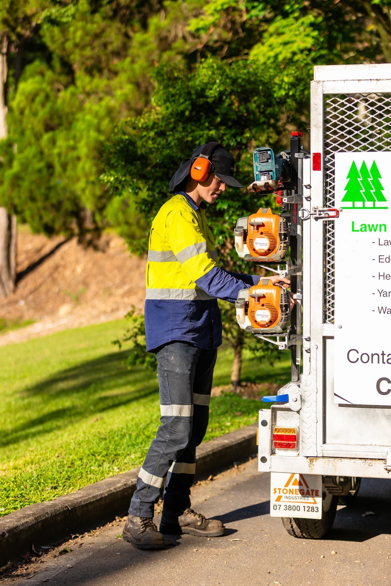 A man is standing next to a lawn mower on the side of the road.