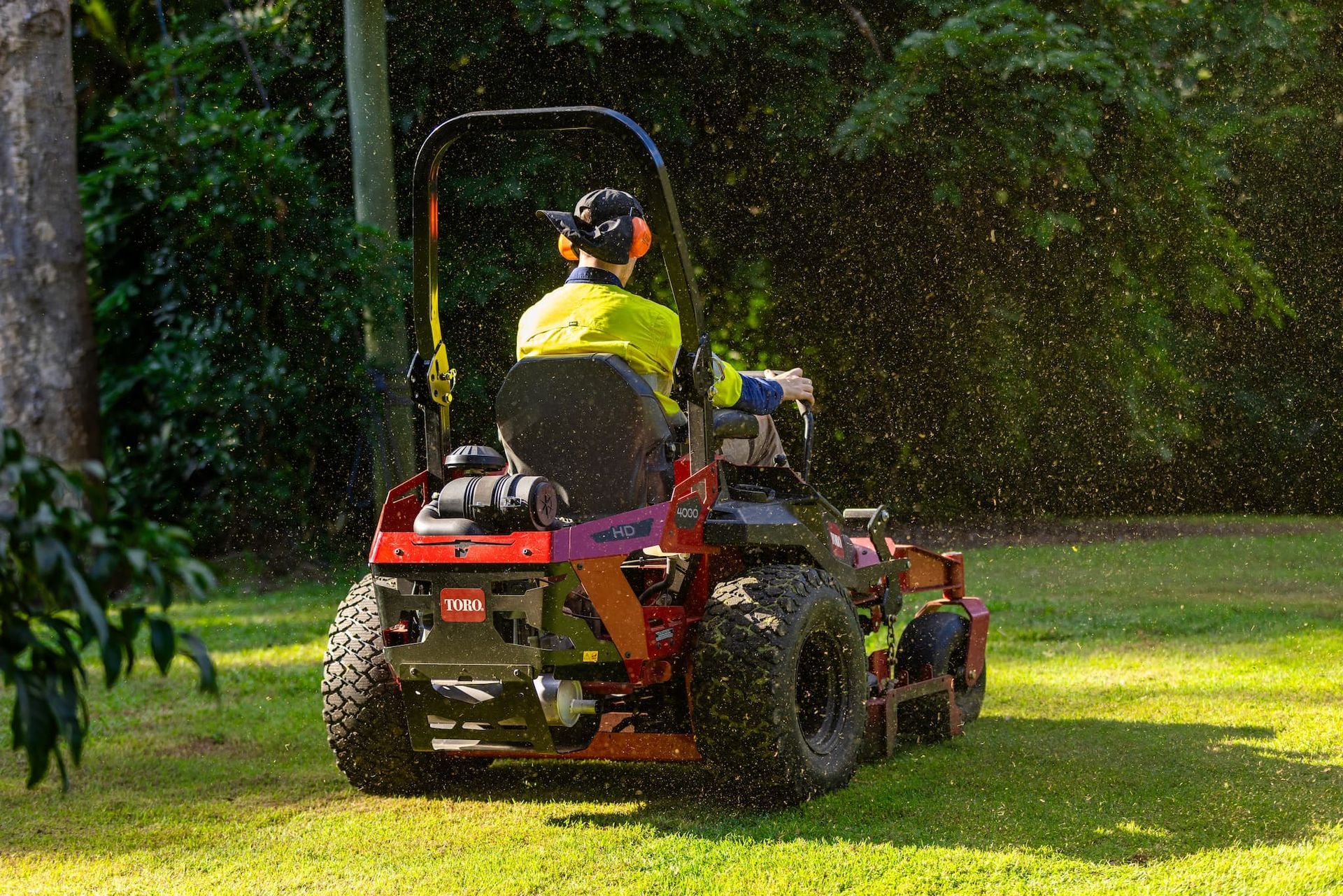 A man is riding a lawn mower on a lush green lawn.