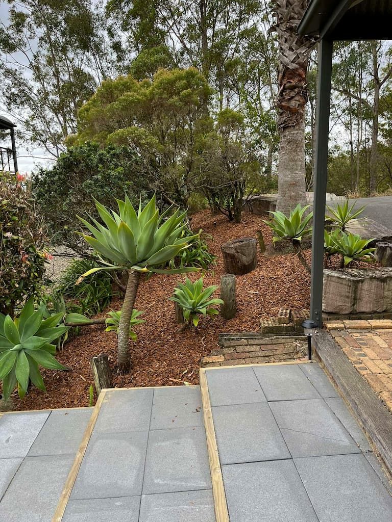 A staircase leading up to a house with a lot of plants and trees in the background.