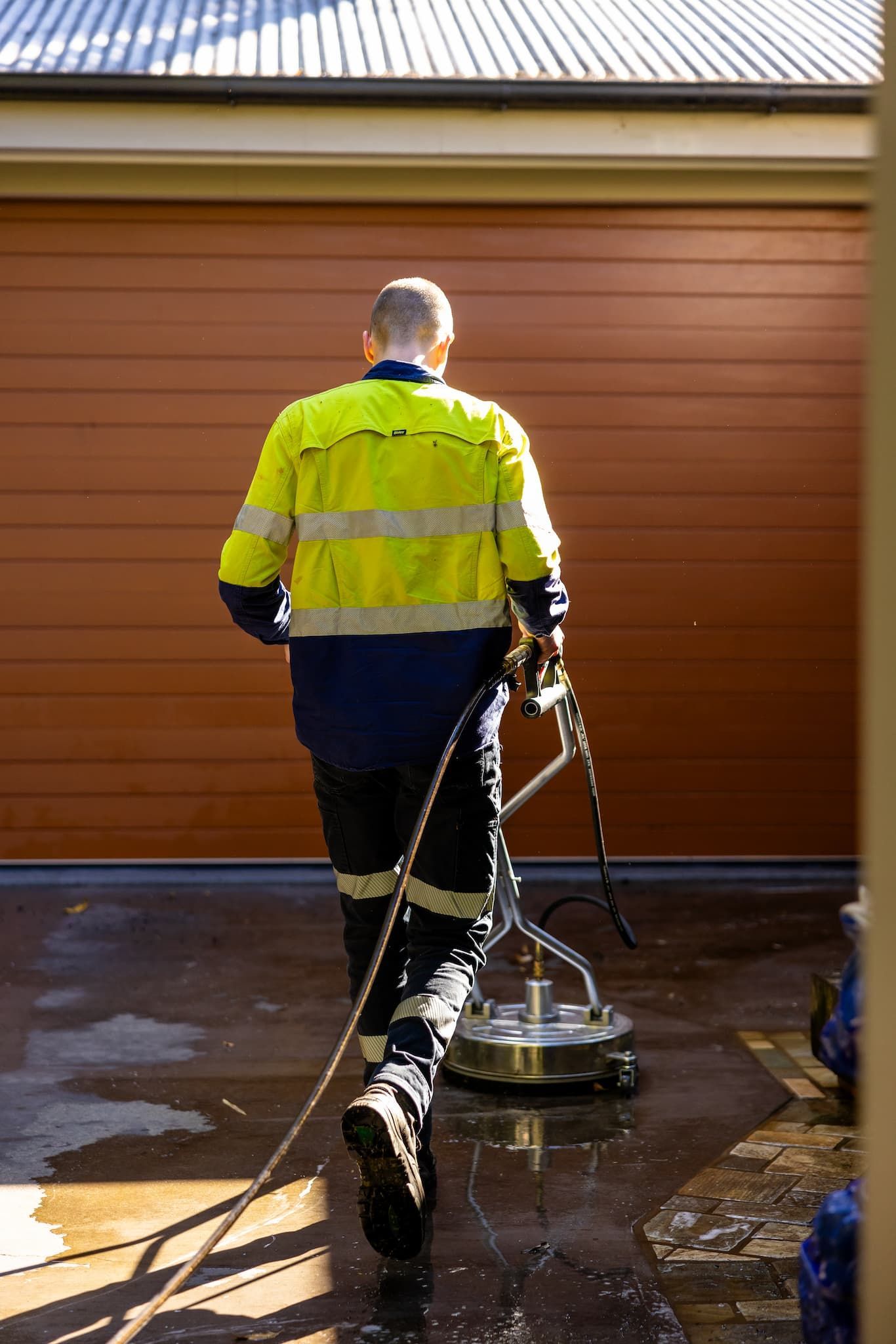 A person pressure washing a home 