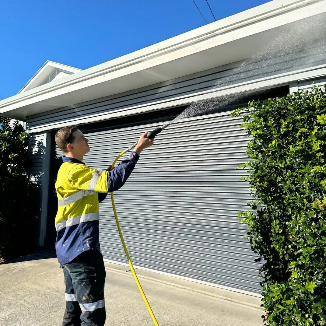 A person pressure washing a home in Brisbane