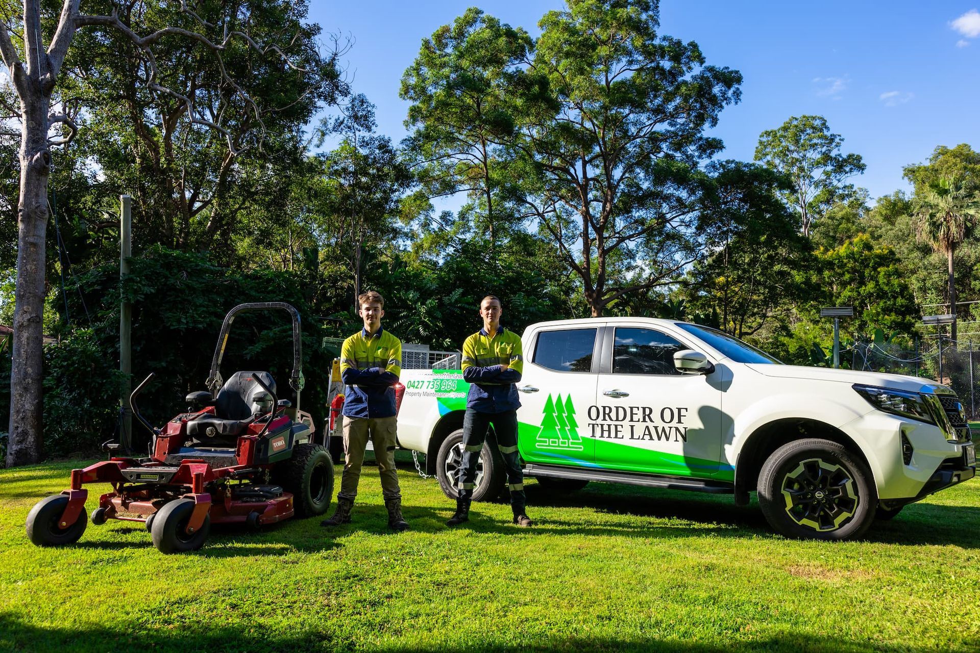 Two men stand by a lawn mower and a white truck with