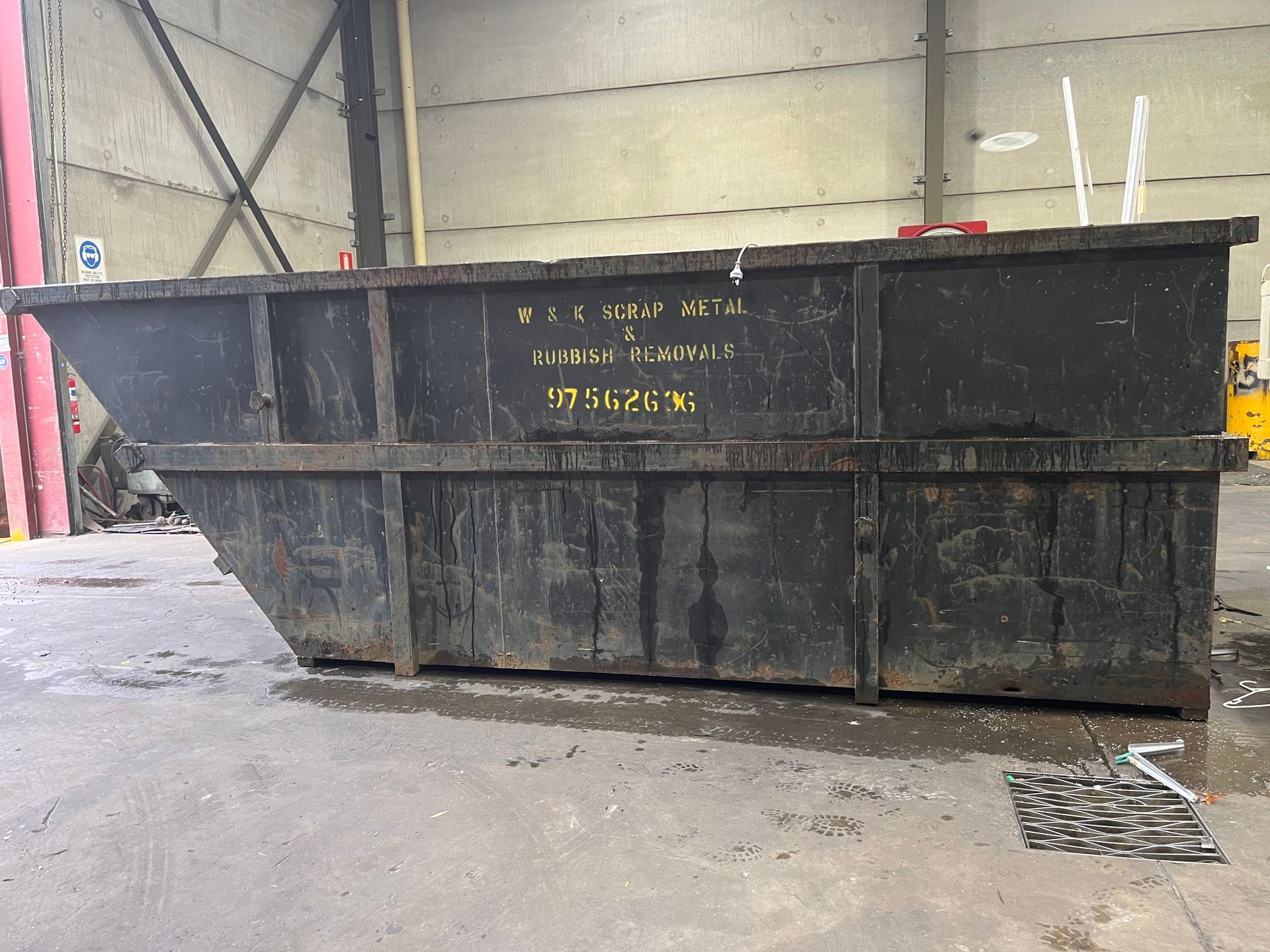 Black industrial dumpster in a warehouse.