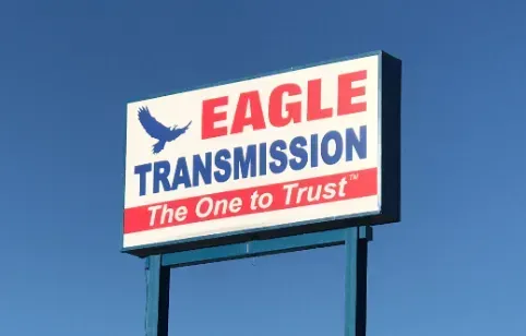 Sign for Eagle Transmission, a blue-and-white rectangle with red lettering against a clear blue sky. Includes a flying eagle graphic.