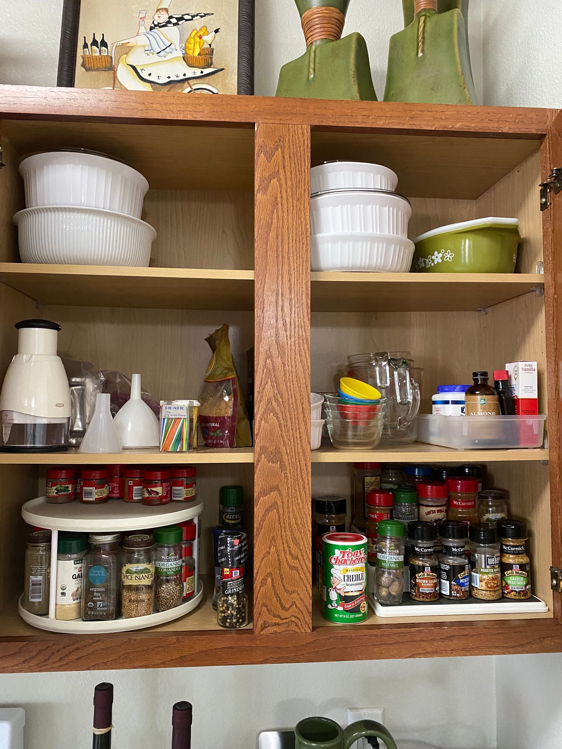 A kitchen cabinet filled with lots of spices and utensils.