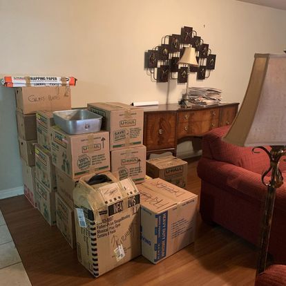 A living room filled with cardboard boxes and a lamp