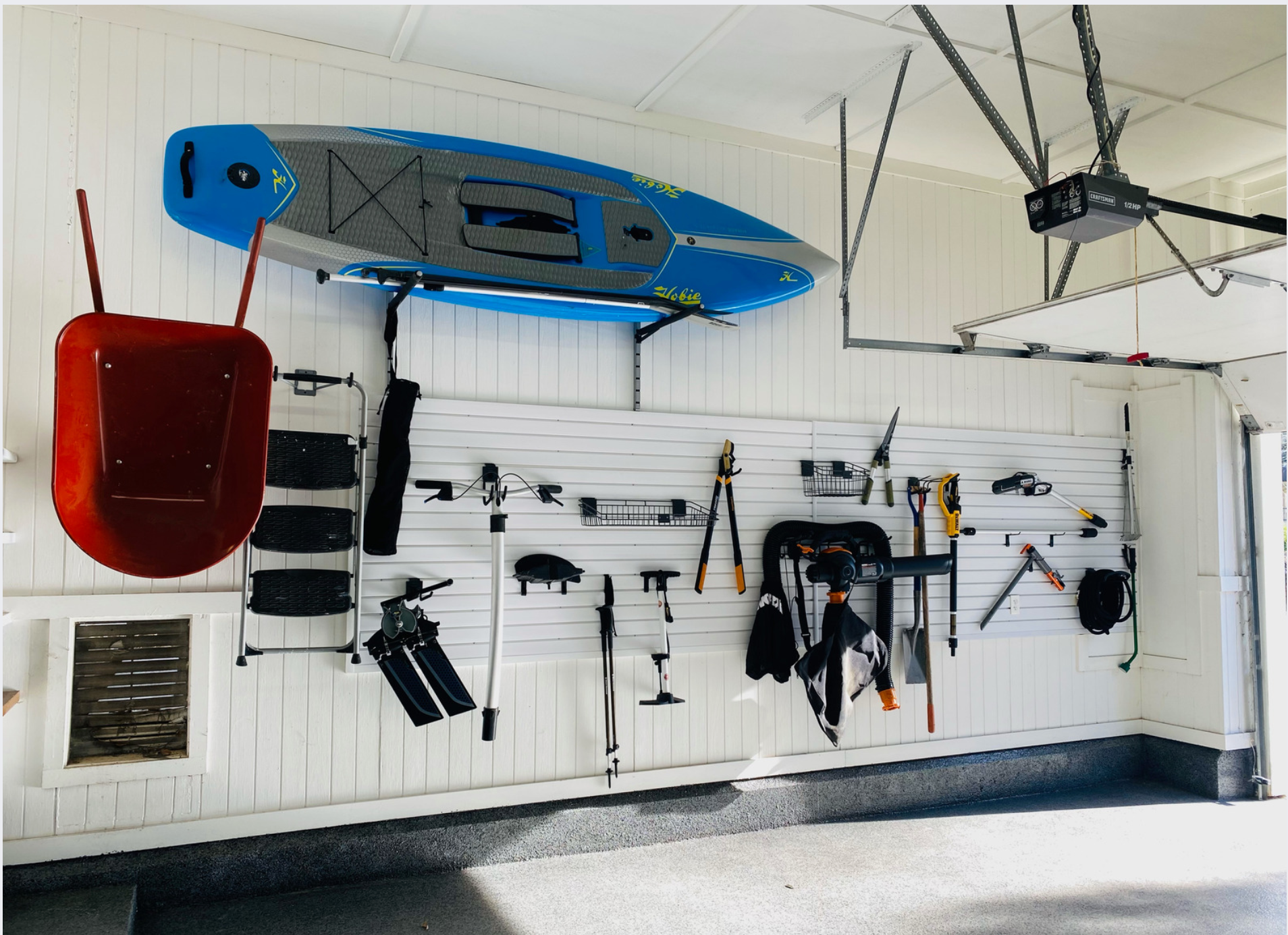A blue kayak is hanging from the ceiling of a garage