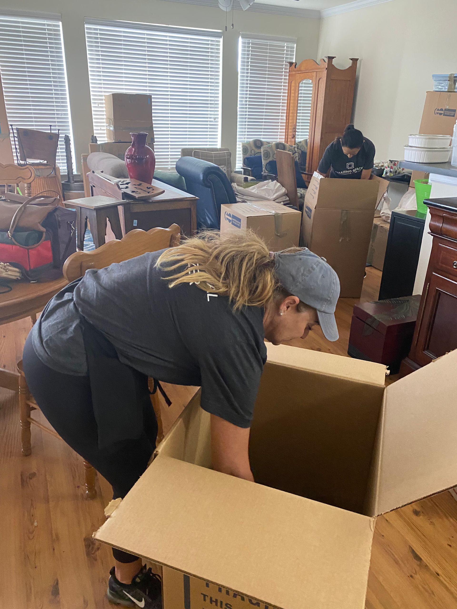 A woman is bending over to open a cardboard box in a living room.