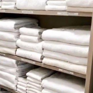 A shelf filled with stacks of white towels.