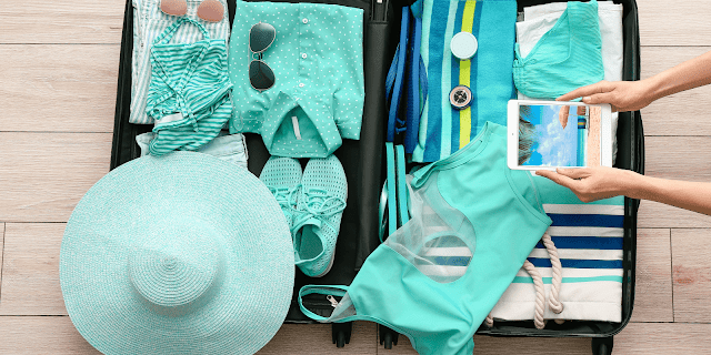 A person is taking a picture of a suitcase filled with clothes.