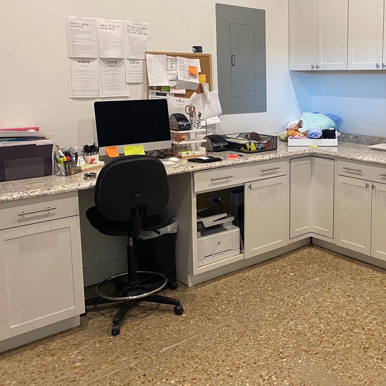 A desk with a computer and a chair in a kitchen.