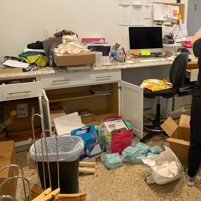 A messy room with boxes and a trash can