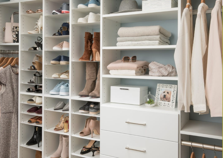 A walk in closet filled with lots of shoes and clothes.