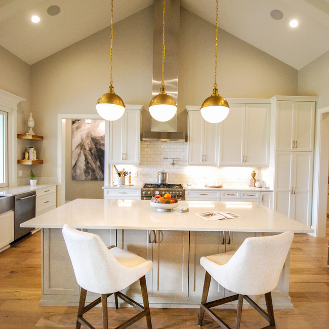 Moving boxes stacked in a room, with a potted plant, a rolled rug, and a wrapped chair.