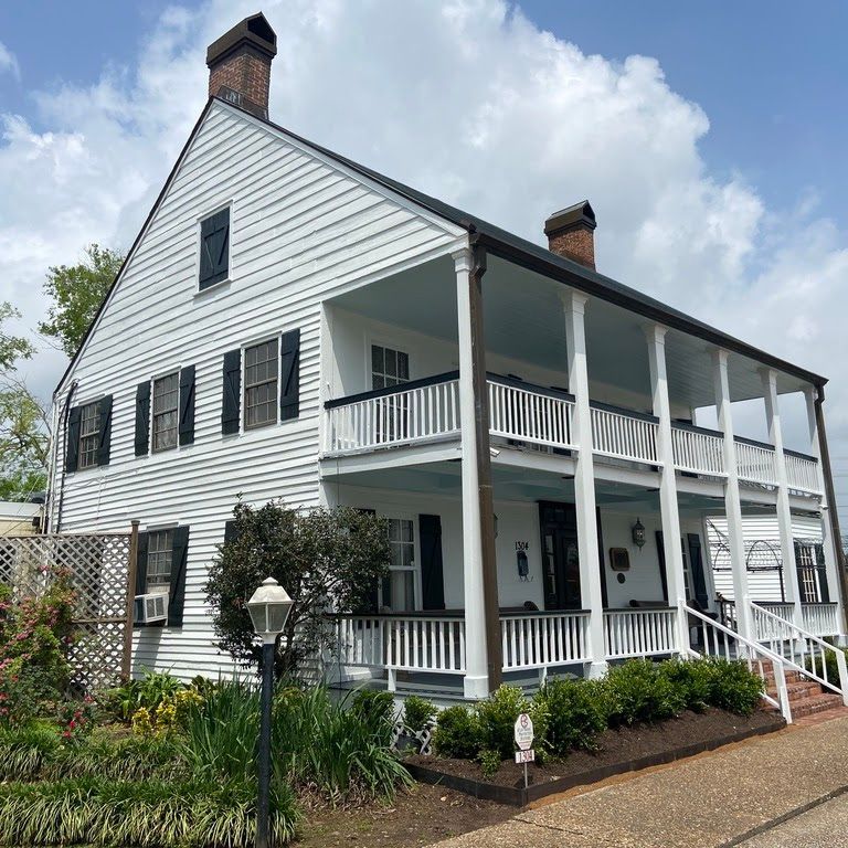 A large white house with black shutters and a porch