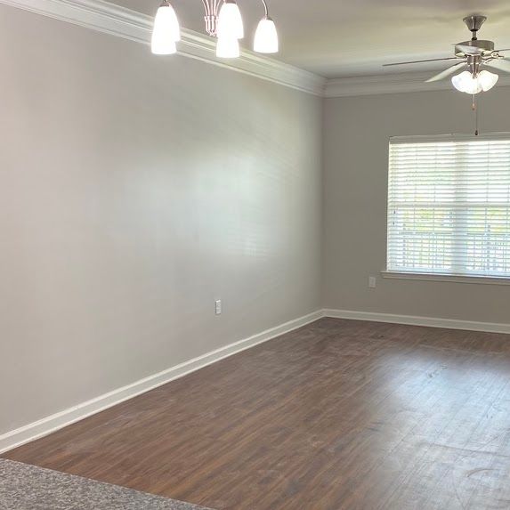 An empty living room with hardwood floors and a ceiling fan.