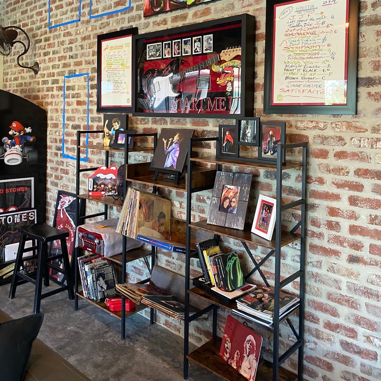 A room with a brick wall and shelves filled with books and pictures
