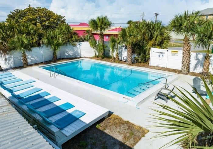 a large swimming pool surrounded by palm trees and chairs